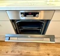 A kitchen with an oven and a wooden decor floor in a 2-room apartment.
