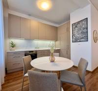A kitchen in a 2-room apartment with light furniture and a wooden decor floor.
