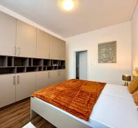 Bedroom in a two-room apartment, with wood-decor flooring and a large wardrobe.