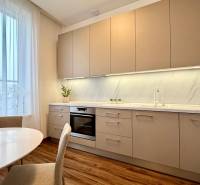 A bright kitchen with a wood-patterned floor and a dining table in a two-room apartment.