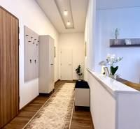 Entrance hall in a 2-room apartment, with a wooden decor floor and a white wall.