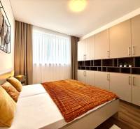 Bedroom in a 2-room apartment with wood-decor flooring, a large wardrobe, and an orange blanket.