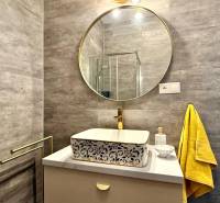A bathroom in a 2-room apartment with a round mirror and a yellow towel.