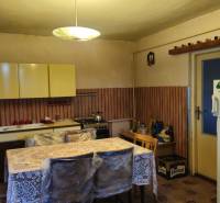 Kitchen in a family house with a dining table, kitchen unit, and refrigerator.
