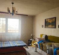 A room in a family house with a bed, a chandelier, boards, and a sofa.