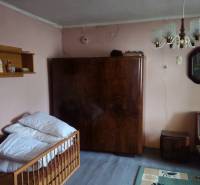 A room in a family house with a sofa, a wardrobe, a chandelier, and shelves on the walls.