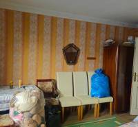 A room in a family house with retro wallpaper, furniture, and toys in plastic bags.