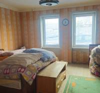 A room in a family house with a bed, a table, and toys, with wooden floor decor.
