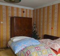 Double room in a family house with wallpaper and wooden wardrobes.