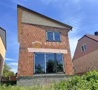 An unfinished family house in Cerová with an unplastered brick facade and a roof.