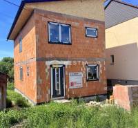 Unfinished family house in Cerová with unplastered brick walls and black window frames.