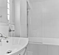 Bathroom in a 2-room apartment with a white sink and a bathtub on the left.