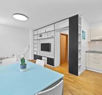 Living room with kitchen, wooden decor flooring, dining table, shelves, and sofa.