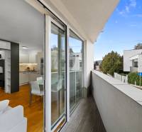 A balcony with a view, leading to a 2-room apartment with a wooden decor floor.