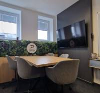 Office seating with a conference table, gray chairs, and green wall decoration.