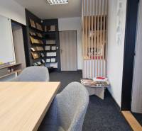 Offices with carpet flooring, a wooden desk, and a bookshelf.
