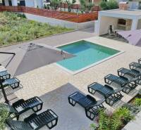 A swimming pool with loungers and umbrellas in a 3-bedroom apartment in Sukošan.