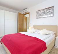 A bright bedroom with white furniture and a red throw in a 3-room apartment.