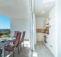 A brightly lit terrace with a dining table and a view of SUKOŠAN. Along with a kitchen.