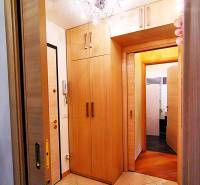 A hallway in a 2-room apartment with sliding doors and a floor with a wooden decor.