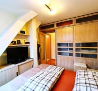 Bedroom in a 2-room apartment with sliding wardrobes and a television, floor with wood decor.