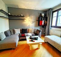Living room in a two-room apartment with a sofa and wooden decor flooring.