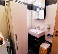 A bathroom in a 2-room apartment with a sink, storage space, and a washing machine.