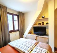Bedroom in a 2-room apartment with a bed, television, and a window with curtains.