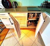 A kitchen in a 2-room apartment with open cabinets, a floor with wooden decor and tiles.