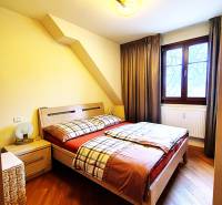 Bedroom with wood-patterned flooring in a 2-room apartment, bed, nightstands, window.