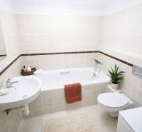 A bathroom in a 2-room apartment with a bathtub and simple furnishings, cream tiles.