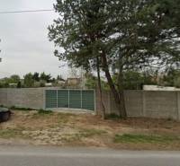 Commercial plots on Dukelská in Bernolákovo with a concrete fence and access road.