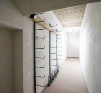 A narrow interior space in a warehouse with metal hooks on the wall.