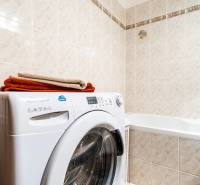 Bathroom with a washing machine in a 3-room apartment; beige tiles, stored towels.
