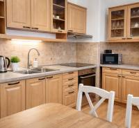 A kitchen in a 3-room apartment with wooden decor, kitchen cabinets, appliances, and a table.