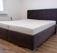Bedroom with a bed and wooden decor flooring in a 3-room apartment.