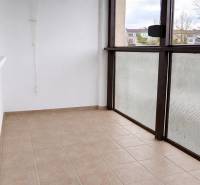 Glazed balcony of a 3-room apartment, tiled floor, view of the surroundings.
