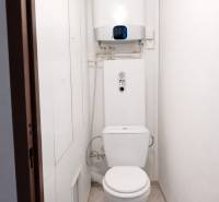 Bathroom with toilet and boiler in a 3-room apartment, light walls and simple design.