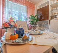 Interior of a family house with a decorated table, glass cabinet, and pink curtains.