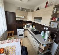 A kitchen in a 4-room apartment with a countertop, stove, wooden cabinets, and a round table.