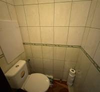 A toilet with tiles, toilet paper in a 4-room apartment.