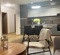 Living room in a 3-room apartment with a kitchen, table, and wooden decor flooring.