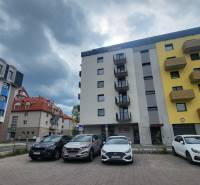 Apartment buildings on Hviezdoslavova Street in Poprad with a parking lot and an overcast sky.