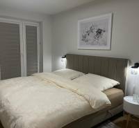 A bedroom in a 3-room apartment with a light bed and subtle wall decor.