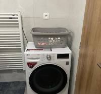 Bathroom with a washing machine in a 3-room apartment, next to a radiator on white tiles.