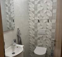 A bathroom in a 3-room apartment with geometric light gray tiles, a sink, and a toilet.