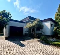 A family house in Ivanka pri Dunaji with a garage and a flower bed, on a paved walkway.