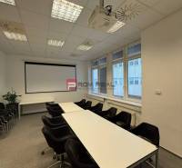 Conference room in offices with a projector, tables, and chairs, ready for meetings.