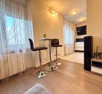 Interior of a 2-room apartment with a wooden decor floor, bar stools, and decorations.