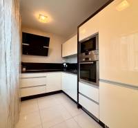 White kitchen with black accents and appliances in a 2-room apartment.